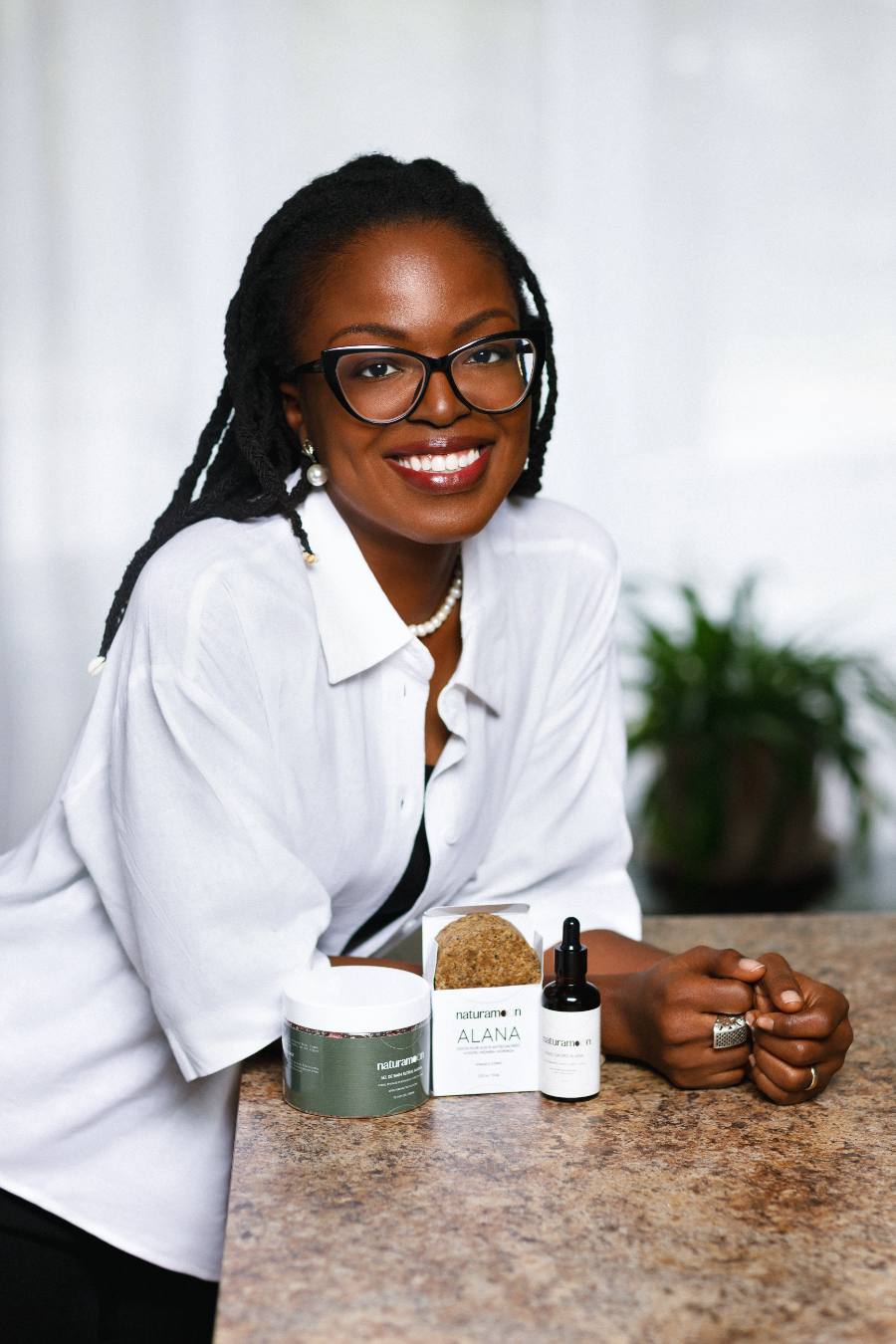 Mouna Akue d'Almeida, fondatrice de NATURAMOON, avec les trois essentiels du rituel ALANA